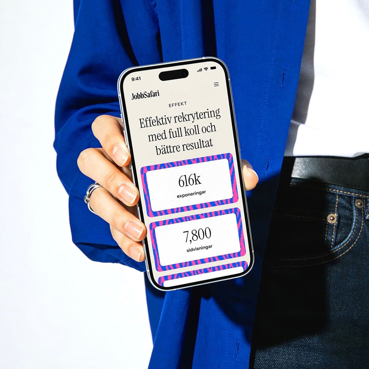 Person in a blue jacket holding a phone displaying Jobbsafari's recruitment performance figures.