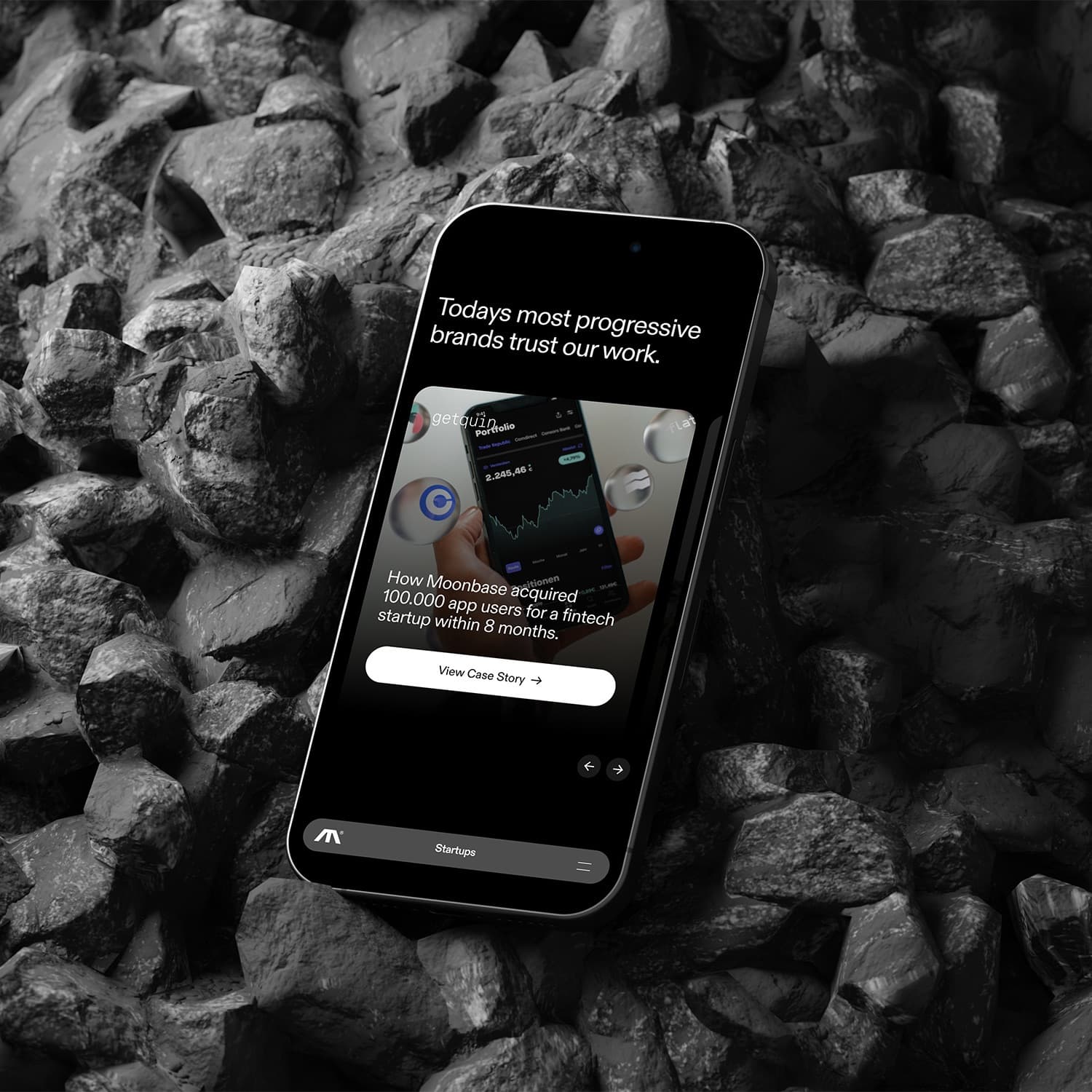 Moonbase's client work page displayed on a phone resting among dark rocks.